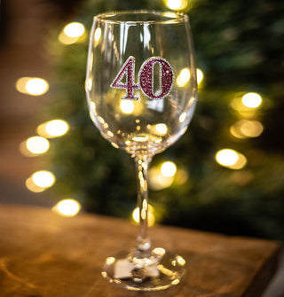 Clear wine glass features a rhinestone-encrusted pink "40" with silver eges on its bowl