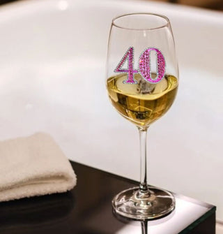 Wine glass with pink rhinestone-encrusted "40" decal on its bowl is partially filled with a beverage