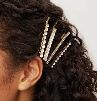 Model wears four rhinestone-encrusted bobby pins in a side-swept hairstyle