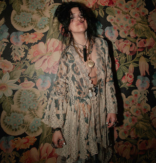 Smiling model standing against a floral backdrop wears a lace open-front mid-length duster with enlarged leopard print