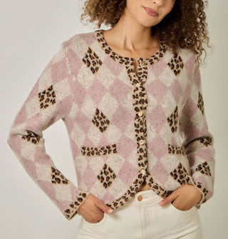Model wears a pink and white diamond print cardigan with contrasting leopard print diamond accents, neckline, button placket, bottom hem, sleeve cuffs, and pocket edges