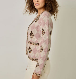 Model wears a pink and white diamond print cardigan with contrasting leopard print diamond accents, neckline, button placket, bottom hem, sleeve cuffs, and pocket edges
