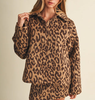 Model touches the collar of a leopard print jacket with an oversized fit and matching cloth-covered buttons, paired with matching skirt