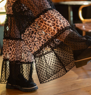 Model kicking out one leg wears a pair of leopard- and black lace-legged wide leg pants with black combat-style boots