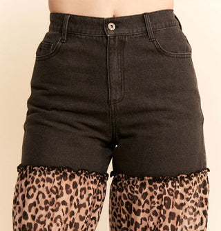 Closeup of the high rise waist on a pair of black jeans with ruched, ruffled leopard print panels on the legs