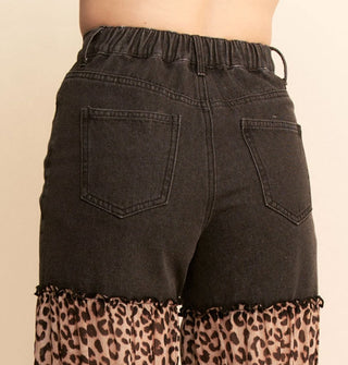 Closeup of the elasticated high rise waist on a pair of black jeans with ruched, ruffled leopard print panels on the legs