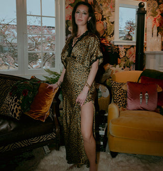 Model wears a full-length satin leopard print dress with black lace trim and thigh-high side slit