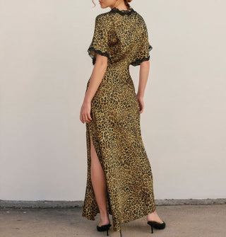 Model facing away from the camera wears a full-length satin leopard print dress with black lace trim and thigh-high side slit