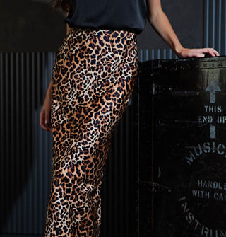 Model posing backstage wears a midi-length leopard print satin skirt