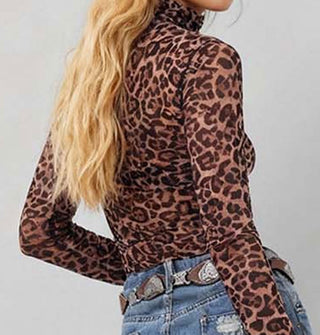 Model wears a long-sleeved leopard print turtleneck with a belted denim skirt