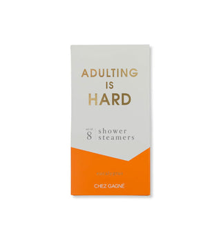 White and orange box of Adulting Is Hard Shower Steamers by Chez Gagné features metallic gold title lettering
