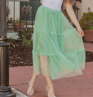 Model wears a seafoam green tulle midi-length skirt with knee-length lining and three horizontal tiers edged with ruffles