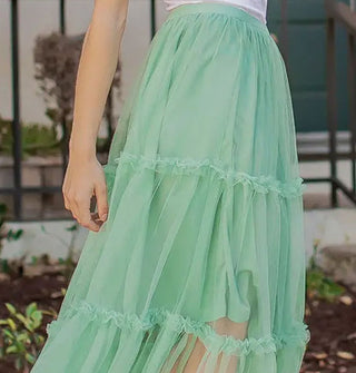 Model wears a seafoam green tulle midi-length skirt with knee-length lining and three horizontal tiers edged with ruffles