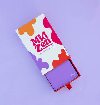 Partially opened red, orange, purple, and white slider box of 52 MidZen Affirmation Cards on a purple surface