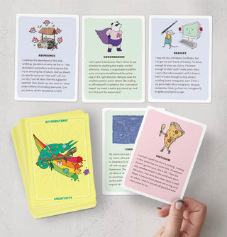 Model's hand holds a card from a spread of Affirmators! Creativity cards