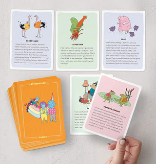 Model's hand holds one card from a spread of Affirmators! Family affirmation cards