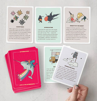 Model holds one card of a spread of Affirmators! Love & Relationships affirmation cards