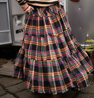 Model twirls in a lack ruffle-tier skirt with colorful plaid print