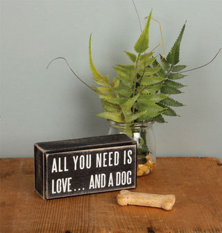 All You Need Is Love...and a Dog box sign sits on a wooden tabletop with plant and dog bone