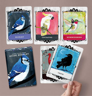 Model's hand holds the Crow card from the Birds Animal Allies oracle deck above a spread of four other cards and the guide booklet