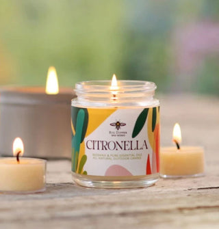 Lit Citronella candle on a rustic wooden tabletop with other lit candles