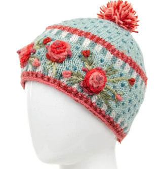 Pale mint green wool beanie with textural pink, red, and green floral embroidery, geometric border designs, and a two-tone pink pom pom on top