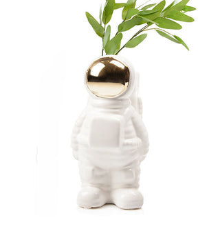 White ceramic and gold astronaut vase holds a sprig of greens