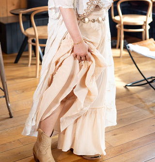 Model wears light peachy-pink, wide-legged pants with horizontal ruffled tiers