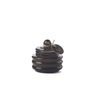 Small black ribbed glass candle jar with knobbed lid, off of which a round tag hangs