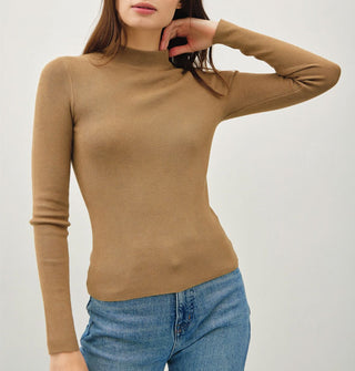 Model wears a long-sleeved khaki-colored mock turtleneck top with blue jeans