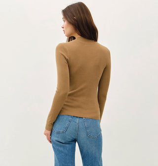 Model facing away from the camera wears a long-sleeved khaki-colored mock turtleneck top with blue jeans