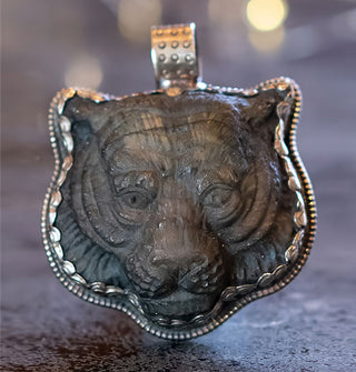 Dark carved labradorite panther face in a scalloped-edge silver pendant setting with rounded top-set bail