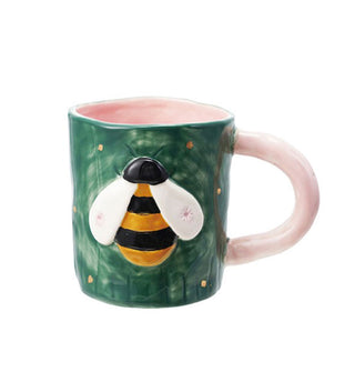 Rustic painted green ceramic mug with pink handle and interior features a black and yellow bee with white wings accented with small stars