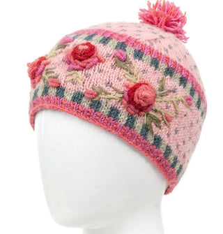 Pale pink wool beanie with textural pink, red, and green floral embroidery, geometric border designs, and a two-tone pink pom pom on top