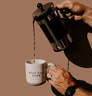 A model pours coffee from a French press into a stoneware Best Dad Ever mug
