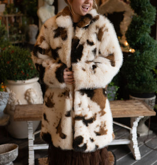 Smiling model wears a white and brown cowhide print faux fur coat