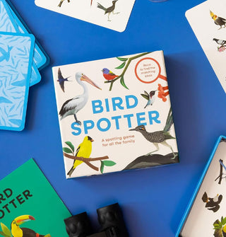 Bird Spotter game box on a blue surface surrounded with cards from the game and a small pair of binoculars