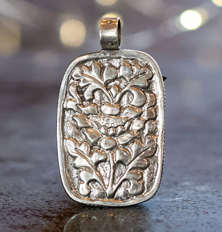 Silver pendant back with ornate floral engraving and rounded top bail