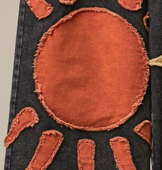 Closeup of a rough-edged orange sun appliqué on black fabric