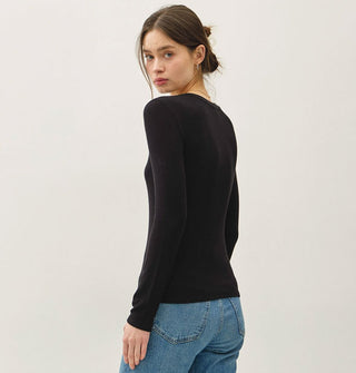 Model wears a black long-sleeved V-neck top with blue blue jeans