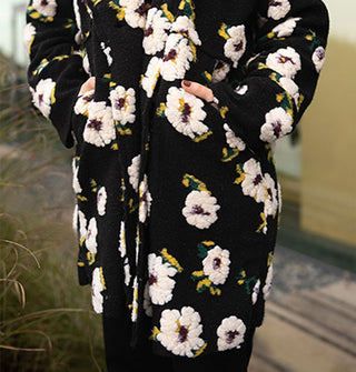 Model wears a black coat with plush white floral pattern