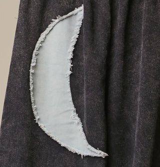Closeup of a rough-edged gray crescent moon appliqué on black fabric