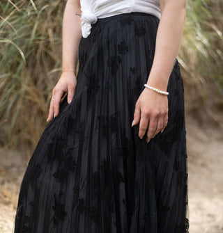 Model wears a black pleated floral tulle skirt with knotted white T-shirt