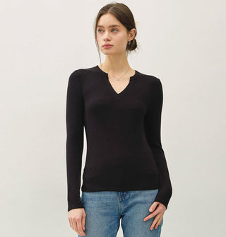 Model wears a black long-sleeved V-neck top with blue blue jeans