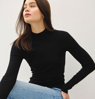 Model wears a long-sleeved black mock turtleneck top with blue jeans