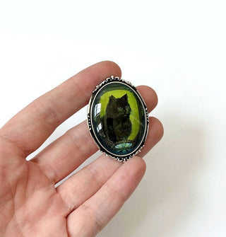 Model's hand holds a black cat portrait pendant