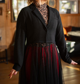 Model wears a tailored black jacket with sheer tulle skirt over a leopard print turtleneck and red pants