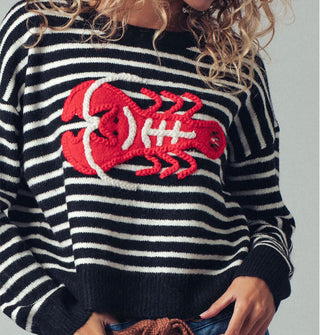 Model wears a black and white striped long-sleeved sweater with a large red and white embroidered lobster design on the front