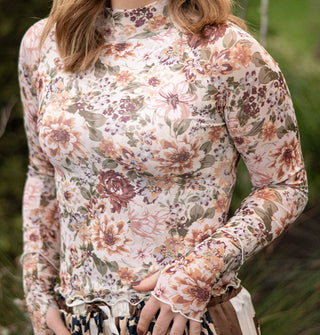 Model wears a long-sleeved pastel floral print top with wavy hems and a mock neckline