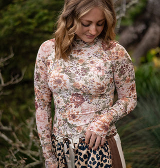 Model wears a long-sleeved pastel floral print top with wavy hems and a mock neckline